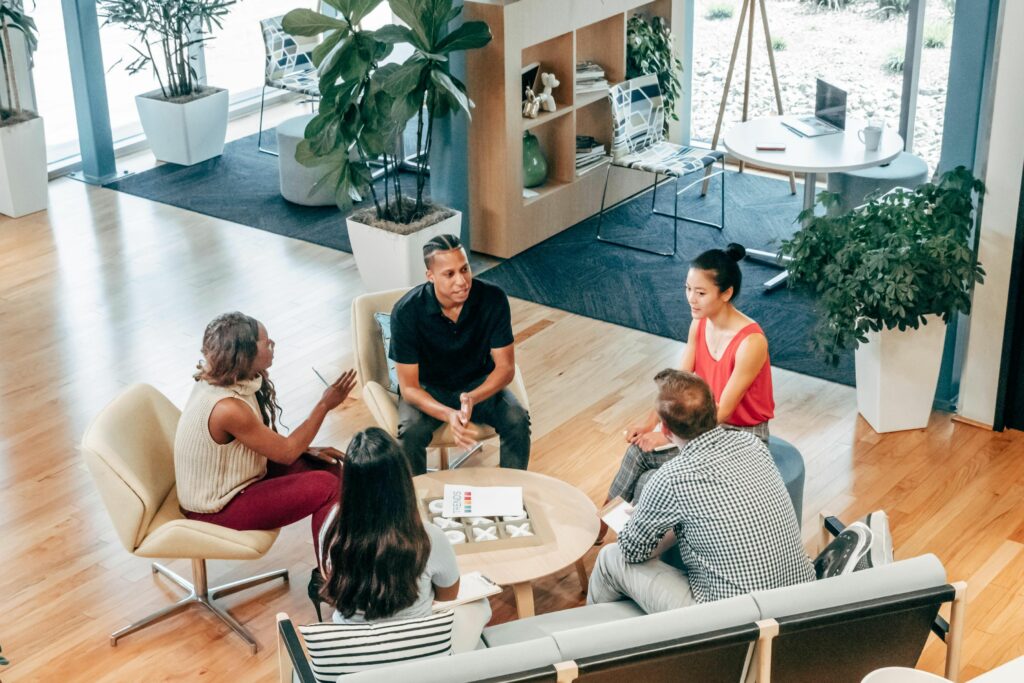 A diverse group of professionals engaged in a collaborative discussion in a modern office lounge, symbolizing effective cross-cultural communication in the workplace.