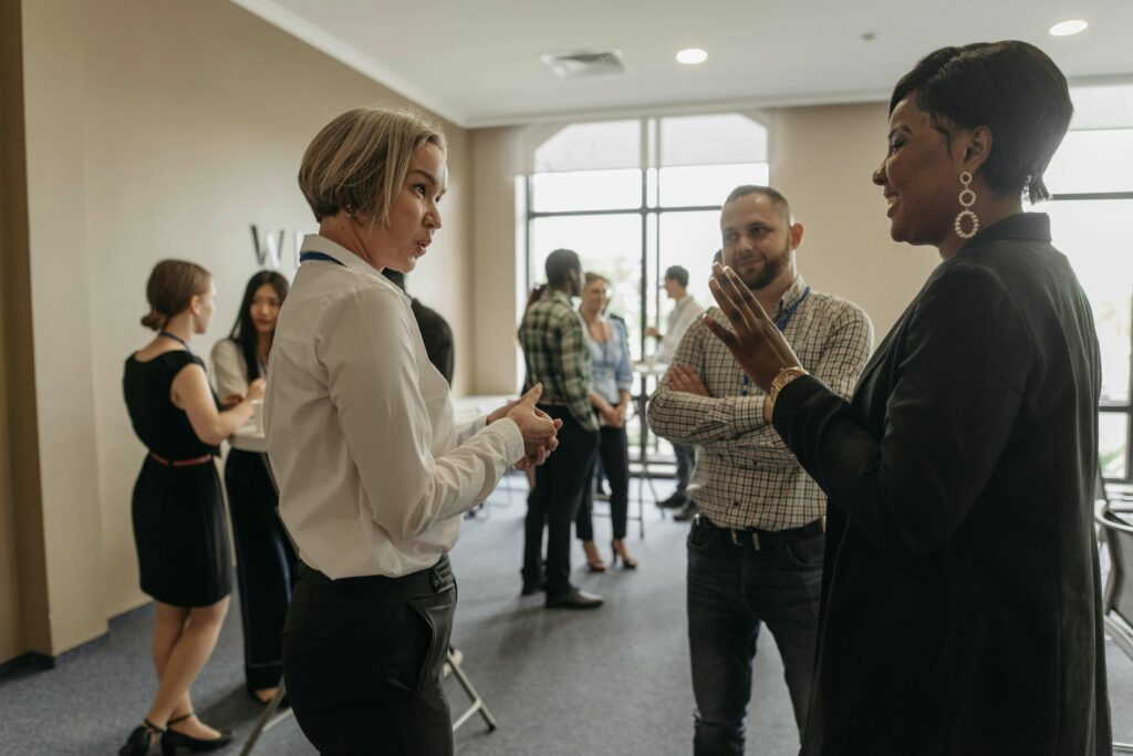 A diverse group of professionals engaging in conversation during a networking event or workshop, symbolizing open dialogue, collaboration, and cultural transformation in the workplace.