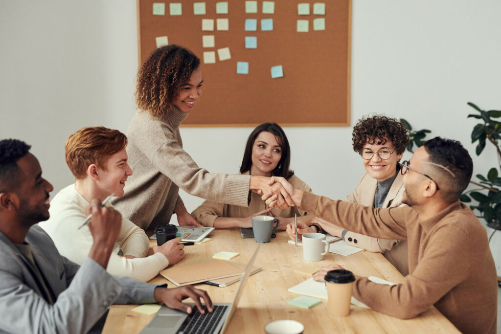 A group of diverse employees gathers around a conference room table at a UK office.