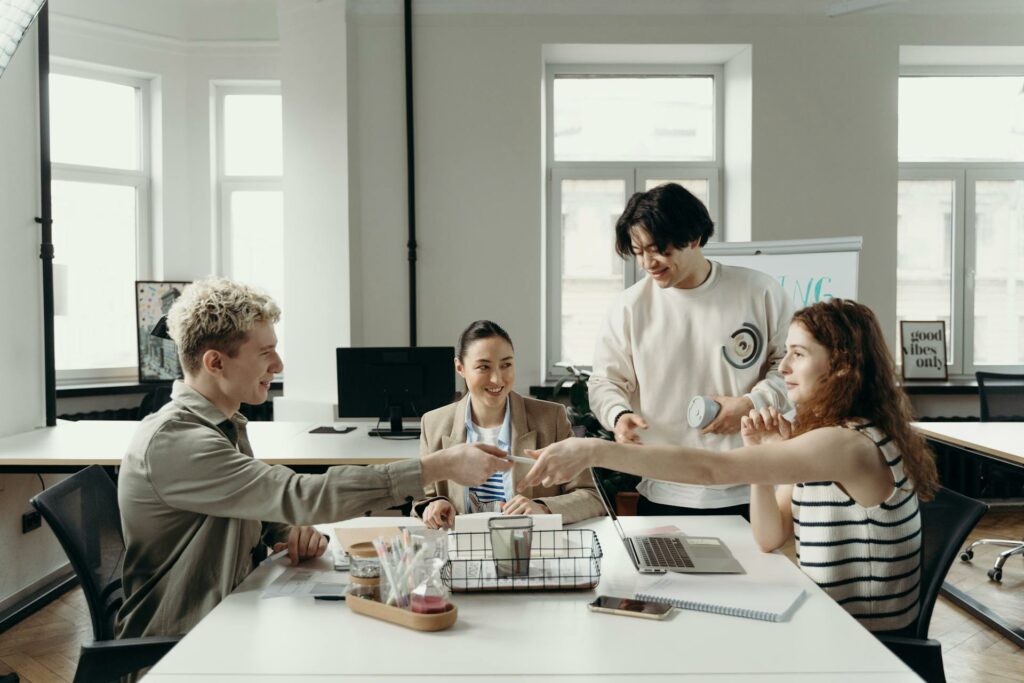 A group of four co-workers sitting together at a desk, discussing ideas