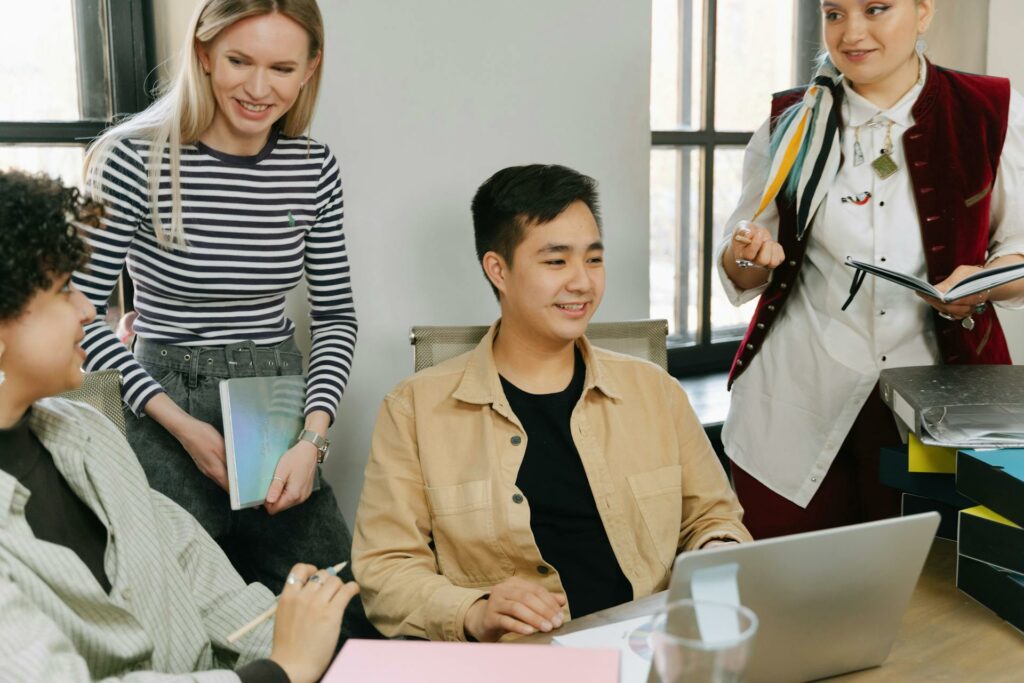 Group of four people working together inside an office, around a desk.