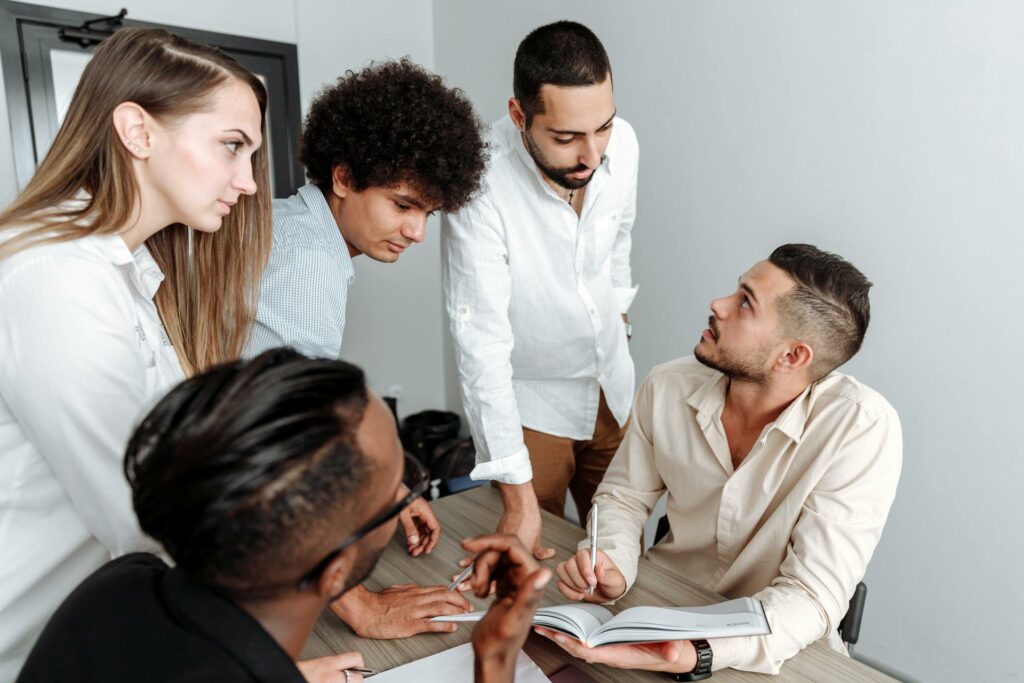 Group of five co-workers brainstorming and working together on a strategy project.